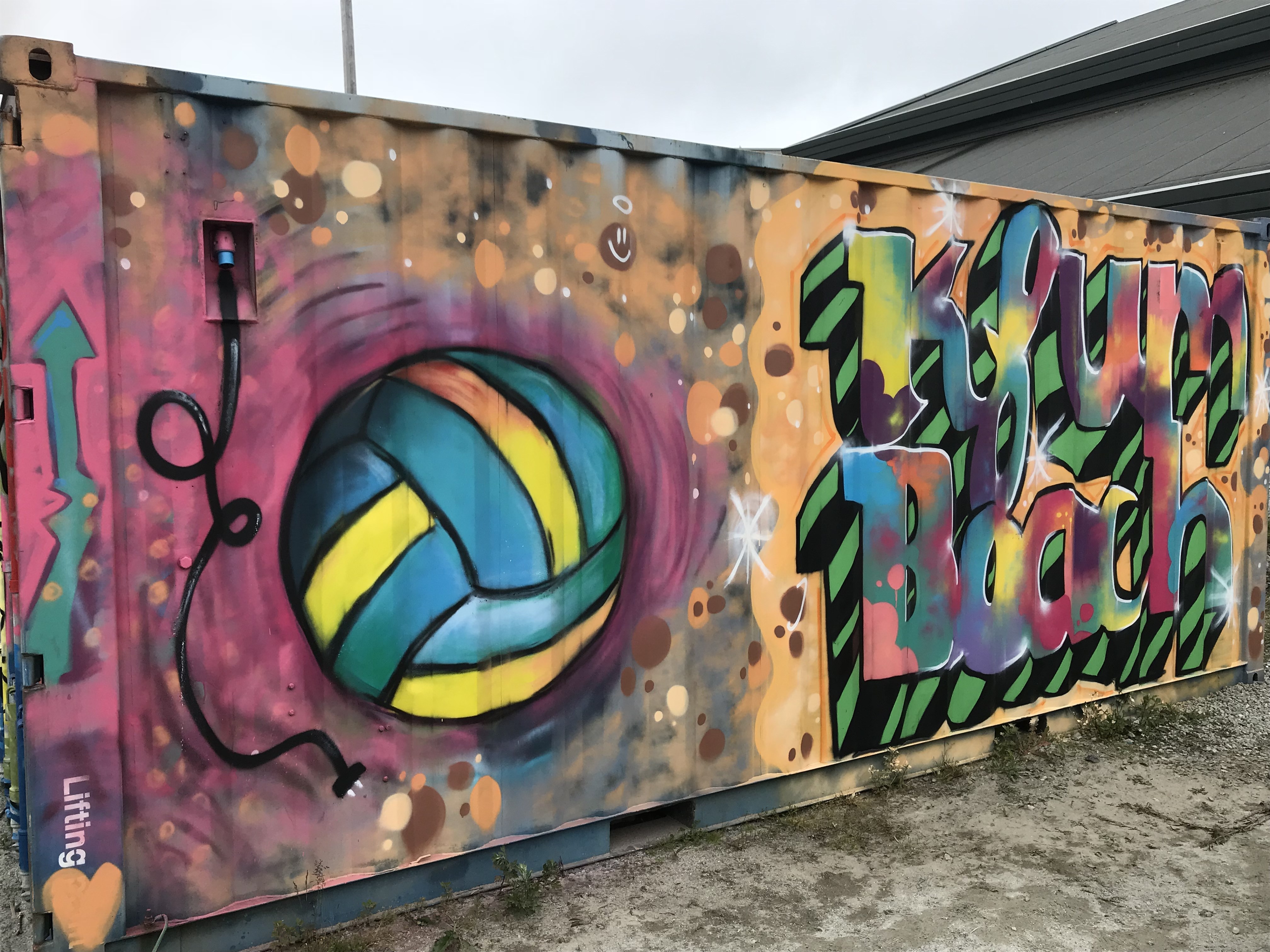 Kontainervegg med street art. En tegning av en volleyball med teksten &quot;kfum beach&quot;