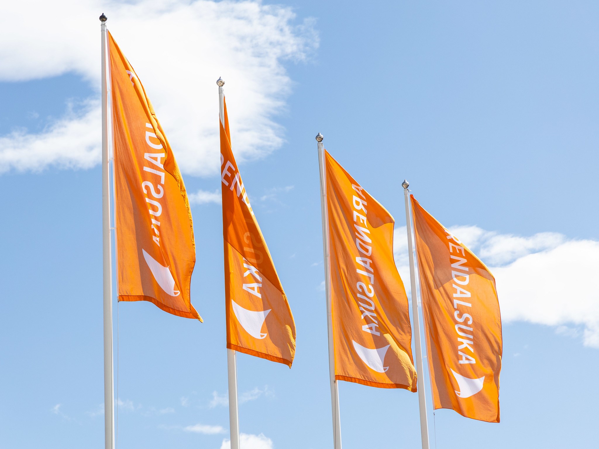 Foto av orange flagg med hvit Arendalsuka-logo mot blå himmel. 
